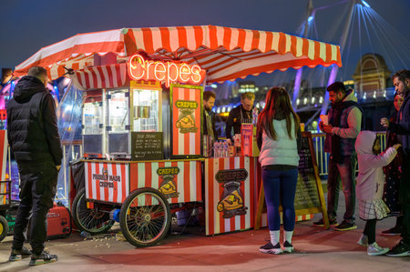 LONDON - April 22, 2023: Night indulgence: Tourists enjoy delicious crepes at Southbank's stall, London's vibrant night scene adding to the culinary delight.のeditorial素材