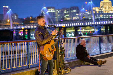 LONDON - April 22, 2023: Urban music: Busker's tunes fill Southbank's evening, creating a cultural...