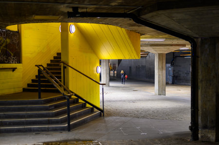 LONDON - April 22, 2023: Vibrant city night: Woman walks along Southbank's covered walkway, yellow wall, and stairs, showcasing urban allure at night.のeditorial素材