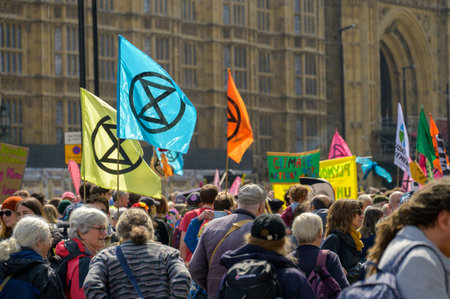 LONDON - April 22, 2023: Extinction Rebellion's powerful message: Protesters with flags and banners high rally outside the Houses of Parliament in London for climate action.のeditorial素材