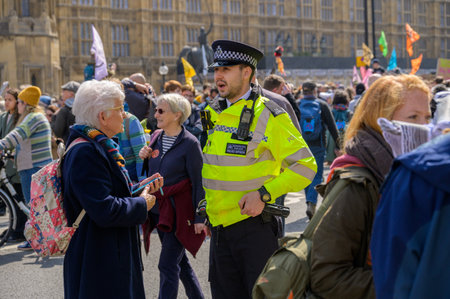 LONDON - April 22, 2023: Human connection amid activism: A Metropolitan Police Officer engages in dialogue with an elderly woman at Extinction Rebellion protest outside London's Houses of Parliament.のeditorial素材