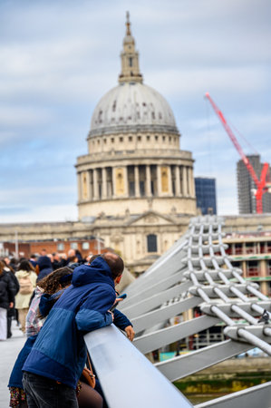 LONDON - April 24, 2023: Cityscape charm: tourists on the millennium Bridge in London, with St Paul's Cathedral adding historical beauty to the backdrop.のeditorial素材