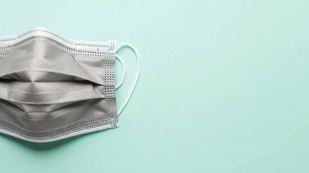 Close-up of a gray protective face mask on a light green background, providing copy space.の写真素材