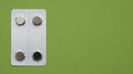 A blister pack of button batteries with varying charge levels on a green background.の写真素材