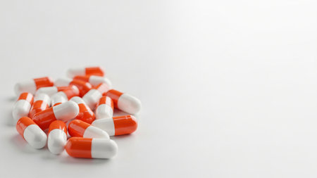 A close-up of a pile of orange and white capsules on a white surface, suitable for medical or pharmaceutical themes.の写真素材