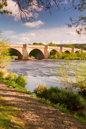 Riverside path at Corbridge with the bridge over the river Tyne leading into Corbidge village on a sunny spring dayの写真素材