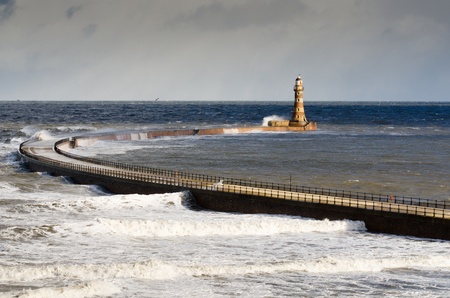 Roker Lighthouse with a rough sea crashing into the north pier at Sunderland harbourの写真素材