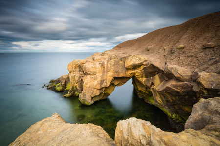 Saddle Rocks in smooth water  Saddle Rocks at Cullercoats Whitley Bay here at high tide using a long exposure to blur the water and cloudsの写真素材