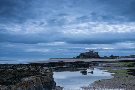 Bamburgh Castle pre dawn  Rocks leading to Bamburgh Castle from the beach at low tide in the blue hour before sunriseのeditorial素材