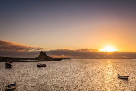 Sunrise at Lindisfarne - The sun rises over the harbour and Lindisfarne Castle on Holy Islandのeditorial素材