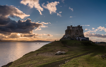 Lindisfarne Castle late afternoon - The warm glow of the suns rays shine from behind a cloud at Lindisfarne Castleのeditorial素材
