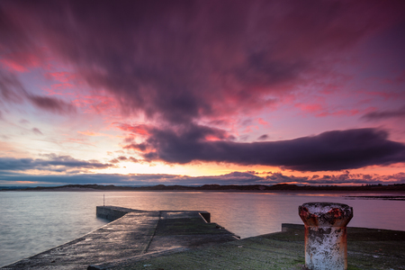 Beadnell Harbour at Sunset, Beadnell is a village on the Northumberland coastline, with a small fishing harbour set into Beadnell Bay.  Disused medieval Lime Kilns sit in the harbourの写真素材