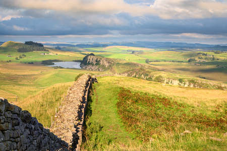 Hadrians Wall winds down to Steel Rigg, a UNESCO World Heritage Site in the beautiful Northumberland National Park, popular with walkers along the Hadrian's Wall Path and Pennine Wayのeditorial素材