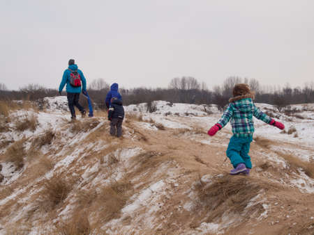 small children walking with dad over dune tops in a winter dune landscapeの写真素材