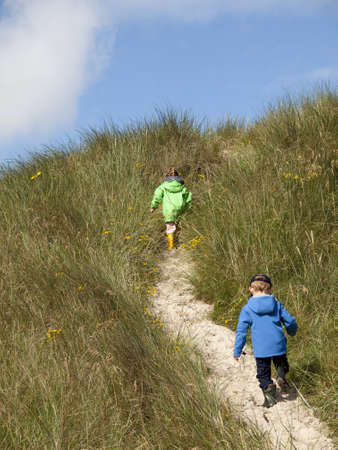 children explore in a dune landscape under blue skiesの写真素材