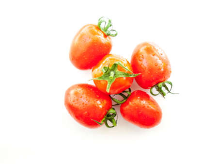 ripe red plum tomatoes  covered in water droplets on a white backgroundの写真素材