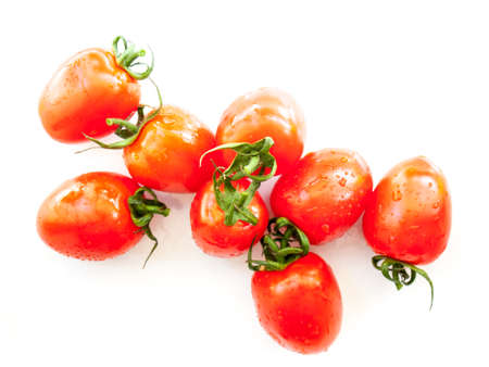 ripe red plum tomatoes  covered in water droplets on a white backgroundの写真素材