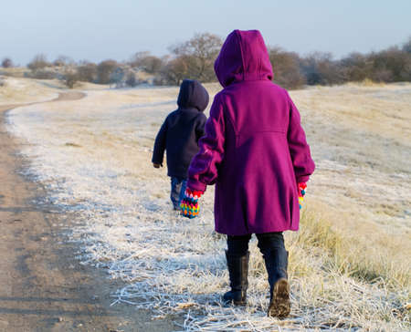 Small children walking in a frosty dune landscapeの写真素材
