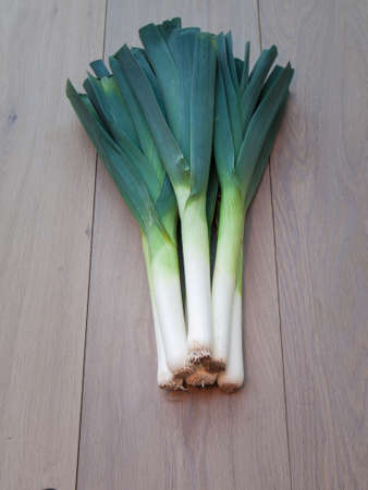 Bunch of fresh leeks on an aged oak wooden table backgroundの写真素材