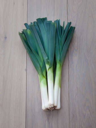bunch of fresh leeks on an aged oak wooden table background