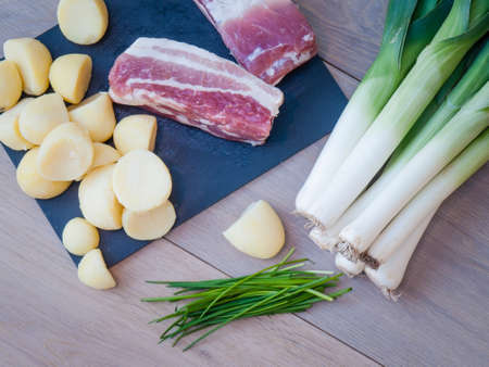 leeks, potatoes, bacon and chives on aged oak and slate background  Ingredients for leek and potato soup on tabletop setting の写真素材