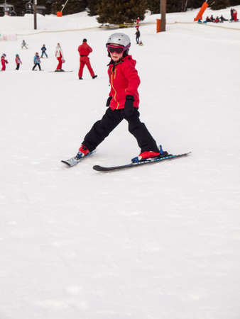 small girl in winter wearing helmet, googles and ski ckothes skiing down a nursery slopeの写真素材
