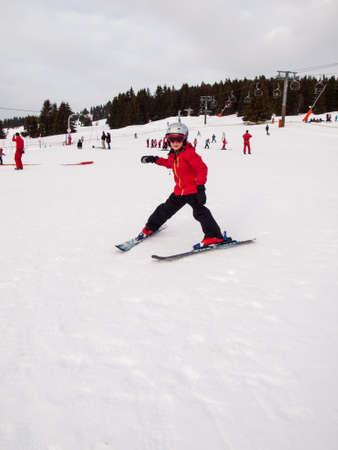 small girl in winter wearing helmet, googles and ski ckothes skiing down a nursery slopeの写真素材