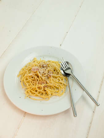 meal of spaghetti carbonara in a rustic table setting with spoon and forkの写真素材
