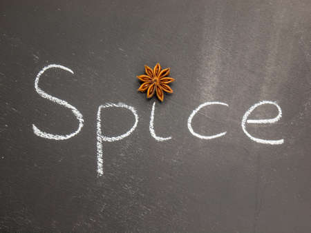 a star anise dotting the i on the word spice written a blackboardの写真素材