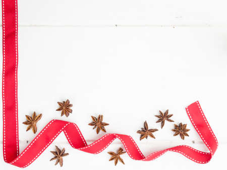 arrangment of star anise with red ribbon on a rustic, aged, white wooden table topの写真素材