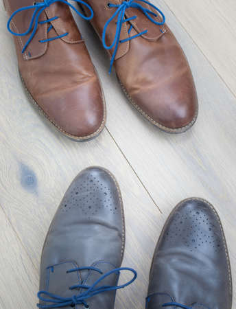 detail of two pairs of grey and brown  leather shoes toe to toe against an aged oak floorの写真素材