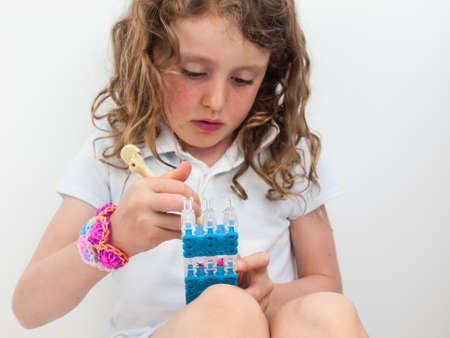 close up of small girl wearing a loom band braclets concentrating hard while loom bandingの写真素材