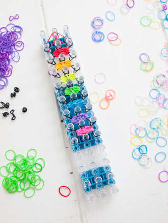 colourful elastic loom bands with band loom against a white table topの写真素材