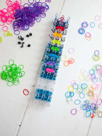 band loom and colourful elastic bands against a white table topの写真素材
