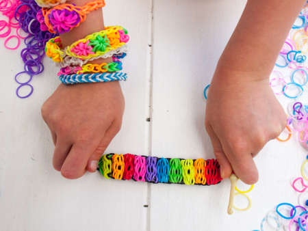 colourful elastic loom band bracelet held in a child hands  against a white table topの写真素材