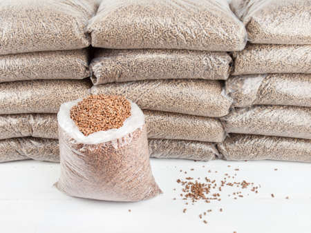 An open bag of wood pellets with a stack of bagged wood pellets behindの写真素材