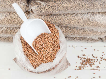 scoop in  bag of wood pellets and a store of bagged wood pellets behindの写真素材