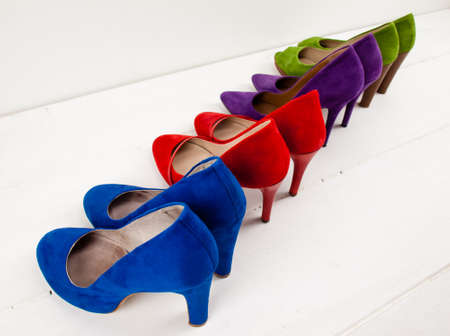 colourful suede stiletto shoes lined up on teh diagonal on a white floor infront of a white wallの写真素材