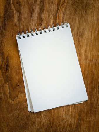 blank page torn out of a  spiral bound notepad against an aged  grained wooden background