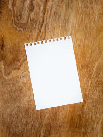 blank page of a spiral bound notepad against an aged  grained wooden backgroundの写真素材