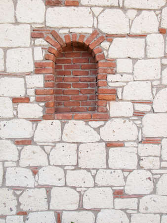 deatil of red brick portal  in a reproduction aged stone wall with grey stonework red tiles and dark grey mortarの写真素材