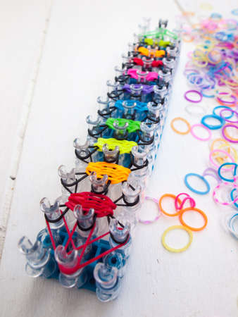 band loom and colourful elastic bands against a white table topの写真素材
