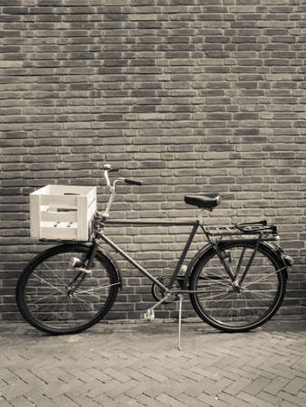 traditional delivery bike with crate against a brick wallの写真素材