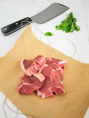 raw lamb chops on brown paper with parcel string  and fresh mint leaves and meat cleaver behindの写真素材