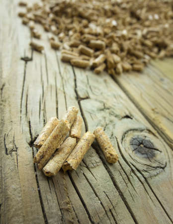 wood pellets against an aged knotted wooden backroundの写真素材