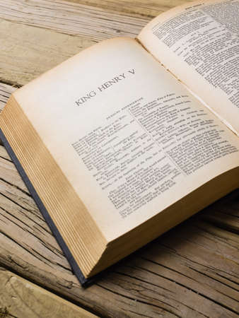 of aged copy of the complete works of shakepseare open at the first page of henry v on a cracked aged wooden surfaceの写真素材