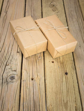 two pbrown paper and string parcels against an aged wooden background
