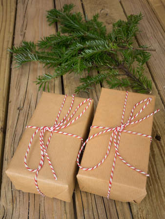 parcels wrapped in  brown paper with red and white string against an aged wooden background with conifer branchesの写真素材