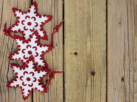 three decorative red and white  christmas snowflakes against a background of rustic wooden boardsの写真素材
