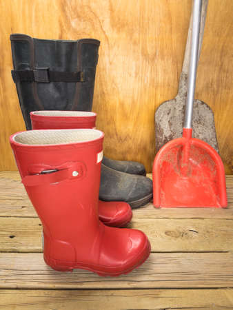 mans green rubber boots and childs red rubber boots in a shed with tools father and son conceptの写真素材